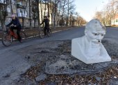 Dos personas en bicicleta pasan frente al busto de Vladimir Lenin, que cubre el cráter de los bombardeos en la carretera en la ciudad recuperada de Lyman, en la región de Donetsk, en el este de Ucrania.