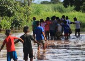 Unos niños caminan en medio de una inundación en la comunidad Rancho Chico perteneciente al municipio de Okinawa