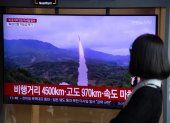 Una mujer observa un misil balístico de Corea del Norte en un lanzamiento anterior.