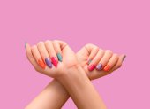 Female hands: one with long colorful nail design and other with short nail design. Glitter nail polish manicure: purple, green, pink, and orange. Female model hands with perfect colorful manicure on p