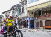 AME3860. PASAJE (ECUADOR), 19/03/2023.- Una pareja en motocicleta pasa hoy, frente a una edificación afectada por un terremoto de magnitud 6,5 en la ciudad de Pasaje (Ecuador). A 446 ascendió la cifra de heridos por el sismo de magnitud 6,5 en la escala abierta de Richter, que se registró el sábado en la provincia del Guayas, en la zona costera de Ecuador, y que dejó 14 fallecidos. EFE/Jhonatan Miranda
