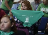 Una mujer muestra hoy una pañoleta verde con la imagen de Beatriz, mientras observa la transmisión en vivo de una audiencia de la CorteIDH, en San Salvador (El Salvador). EFE/Rodrigo Sura
