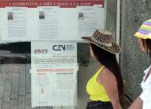Dos mujeres pasan frente a unos carteles informativos sobre el proceso electoral del domingo.