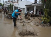 Personas ayudan a remover el lodo en una calle afectada por las lluvias, en el balneario de Punta Hermosa al sur de Lima (Perú), en una fotografía de archivo.