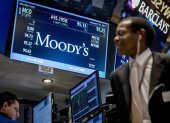 Bolsa.- Una pantalla muestra la información del ticker de Moody"s mientras los operadores trabajan en el piso de la Bolsa.