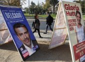 Personas caminan frente a carteles de propaganda electoral para consejeros Constitucionales, el 27 de abril 2023, en Santiago (Chile). Chile celebra este domingo sus segundas elecciones constituyentes en dos años, pero el contexto actual dista mucho de la efervescencia de 2021, cuando aún estaba presente el estallido de 2019, y la hoja de ruta acordada ahora para escribir la nueva Constitución es muy diferente. EFE/Elvis González