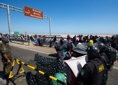 Policías peruanos (d) y chilenos vigilan a cientos de migrantes varados en la frontera, en Arica (Chile).
