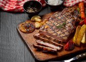 Grilled beef steak on the dark wooden background.