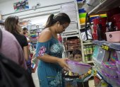 Una persona revisa junto a su hija recipientes plásticos usados para conservar alimentos.