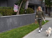 Evidencia. Una mujer pasea con su perro junto a un anuncio de alquiler de departamentos en Los Ángeles.