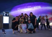 Turistas extranjeros se toman una foto frente a Dongdaemun Design Plaza en Seúl, Corea del Sur, iluminado de púrpura la noche del 12 de junio de 2023, como parte de un festival de dos semanas para celebrar el décimo aniversario de la sensación mundial del K-pop BTS debut, que cae el 13 de junio.