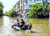 Personas se mueven en un bote inflable por las calles de la inundada ciudad de Jersón.