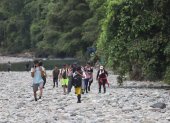 Migrantes de diversos países atraviesan una zona de piedras junto a un río en la zona del Darién, en Panamá