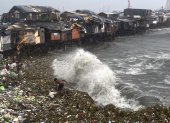 Un hombre se ve sorprendido por una ola mientras rescata materiales desperdigados por la orilla en Manila Bay, Filipinas, este miércoles.
