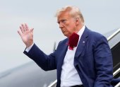 Donald Trump saluda a los presentes mientras se baja de su avión, en su camino a enfrentar un juez por acusaciones federales de conspirar para revertir las elecciones 2020.