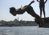 En la imagen de archivo, una persona se sumerge en las aguas del Bósforo para refrescarse, con la mezquita de Süleymaniye al fondo, en Estambul, Turquía.
