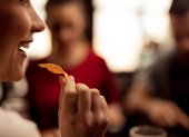 Close up of young woman eating tortilla chips while having fun with her friends in a tavern.