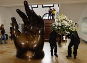 Empleados dejan un arreglo floral junto a la escultura La Mano de Fernando Botero, en el Museo Fernando Botero en Bogotá (Colombia).