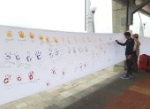 Personas acuden para dejar su huella de la mano en colores de la bandera sobre la lona y escribir un mensaje de paz