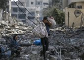 Una mujer palestina (L) sentada entre los escombros del barrio destruido de Al-Ramal tras un ataque aéreo israelí en la ciudad de Gaza, el 10 de octubre de 2023.