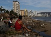 Personas permanecen sentadas junto a los escombros causados por el huracán Otis hoy, en el balneario de Acapulco, en el estado de Guerrero (México)