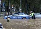Milán. Un par de agentes empujan a un patrullero, afectado por el agua.