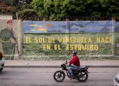 Un hombre conduce una moto frente a un mural que dice "El sol de Venezuela nace por el esequibo", el 2 de noviembre de 2023, en Caracas (Venezuela).