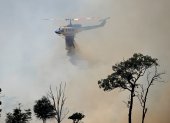 Un helipcótero lanza agua sobre una zona afectada por el fuego, que comenzó en una plantación de pinos en el barrio de Gnangara, un área rural y residencial del noreste de Perth.