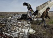 Residentes locales recogen chatarra de un avión de combate estrellado en la región de Kharkiv, Ucrania.