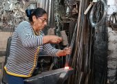 Lucila con el combo y cincel golpea una manija contra el yunque.