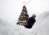 Una mujer camina junto a un árbol de Navidad cubierto de nieve tras una fuerte nevada en Moscú, Rusia, el 15 de diciembre de 2023.