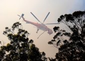 Un helicóptero de los bomberos sobrevuela un incendio forestal en Australia..