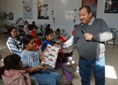 El pastor Juan Fierro (d) reparte regalos a migrantes que pasan la Navidad en el albergue "El buen samaritano", el 24 de diciembre de 2023, en Ciudad Juárez Chihuahua (México).