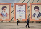 Dos hombres pasan frente a los retratos del líder supremo de Irán, Ali Jameneí, y ayatolá Ruholá Jomeiní durante la conmemoración del 44º aniversario del triunfo de la Revolución Islámica en Teherán.