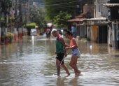 Habitantes transitan hoy por una calle inundada tras las lluvias de los últimos dos días, en el municipio de Duque de Caxias, en la región Baixada Fluminense, área metropolitana de Río de Janeiro (Brasil).