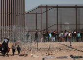 Ciudad Juárez. Migrantes se abren paso a un costado de la cerca de alambres en la frontera que divide a México de los EE. UU.