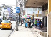 Espacios. Usuarios de buses se protegen de los rayos solares en los exteriores de un inmueble en el centro de Guayaquil mientras esperan por sus unidades.