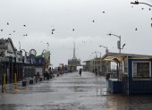 Una persona recorre el muelle de Santa Mónica sosteniendo un paraguas en medio la tormenta azota el sur de California.