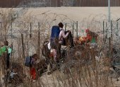 Migrantes intentan cruzar la cerca de alambres en la frontera que divide a México de los Estados Unidos.