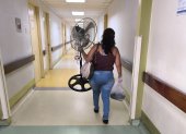 Una mujer lleva un ventilador a la sala donde está internado su paciente, en el hospital Teodoro Maldonado Carbo, del IESS.