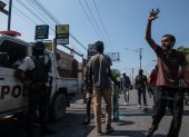 Manifestantes contra la situación política y social de Haití tras la renuncia del primer ministro Ariel Henry pasan junto a un carro policial.