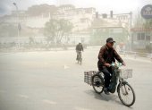 Un hombre sobre una bicicleta después de una tormenta de arena en China.