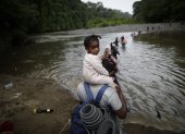 Una persona traslada a un menor mientras atraviesa un sector de la selva del Darién, en algún punto de la frontera entre Colombia y Panamá.