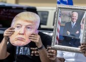 Washington. Dos personas aparecen con un retrato de Biden y una máscara de Trump, en media campaña.