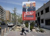 Una mujer pasa junto a un cartel que muestra fotografías del general de brigada iraní Mohammad Reza Zahedi (R), comandante de los Quds del Cuerpo de la Guardia Revolucionaria Islámica (CGRI)