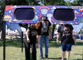 Una familia mira a través de un par de gafas gigantes especiales para el eclipse solar en el Veterans Memorial Park en Dripping Springs, Texas