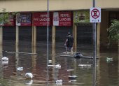 Un hombre camina en una calle inundada de agua y basura en un centro comercial este lunes, en Porto Alegre (Brasil).