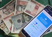 Se muestran billetes junto a un celular con la aplicación del diario digital independiente El Toque,