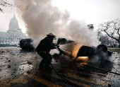 Un bombero apaga un auto en llamas durante enfrentamientos entre la policía y personas que protestan a las afueras del senado durante un debate este miércoles, en Buenos Aires (Argentina). Manifestantes y policías protagonizan un choque este miércoles a las puertas del Senado de Argentina mientras la cámara legislativa debate la ley de Bases, el proyecto estrella del Gobierno, con el que el presidente Javier Milei pretende implementar un paquete de reformas económicas de gran calado. EFE/ Juan Ignacio Roncoroni