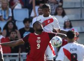 El delantero canadiense Cyle Larin (L) y el defensor peruano Miguel Araujo (R) desafían el balón durante la primera mitad del partido.